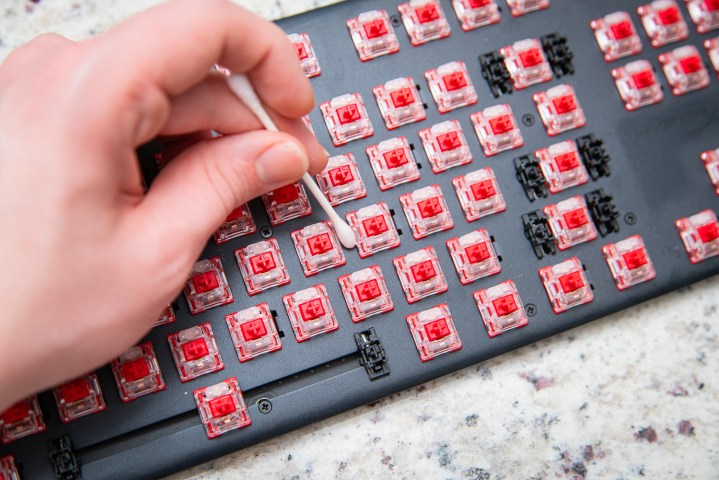 شخص ينظف لوحة المفاتيح باستخدام قطعة قطن.