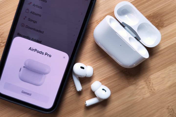 Apple AirPods Pro 2 بجوار iPhone 14 وعلبة الشحن.