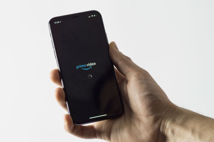 شخص يحمل هاتف iPhone الذي يقوم بتشغيل تطبيق Amazon Prime Video