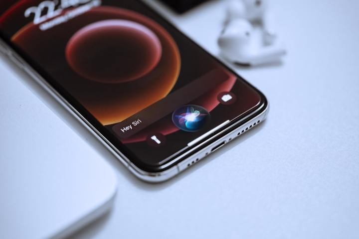 جهاز iPhone على طاولة مع تشغيل الرسوم المتحركة لتنشيط Siri على الشاشة.
