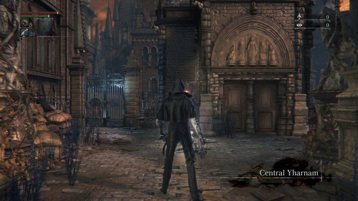 الشخصية الرئيسية في لعبة Bloodborne تقف أمام أحد المباني.