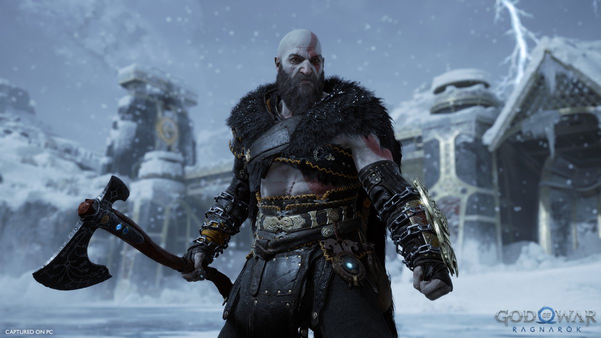 Kratos wears the Armor of the Black Bear set against the snowy backdrop of the frozen Lake of Nine. The set prominently a heavy black fur cloak draped over his shoulders with gold threaded accents. 