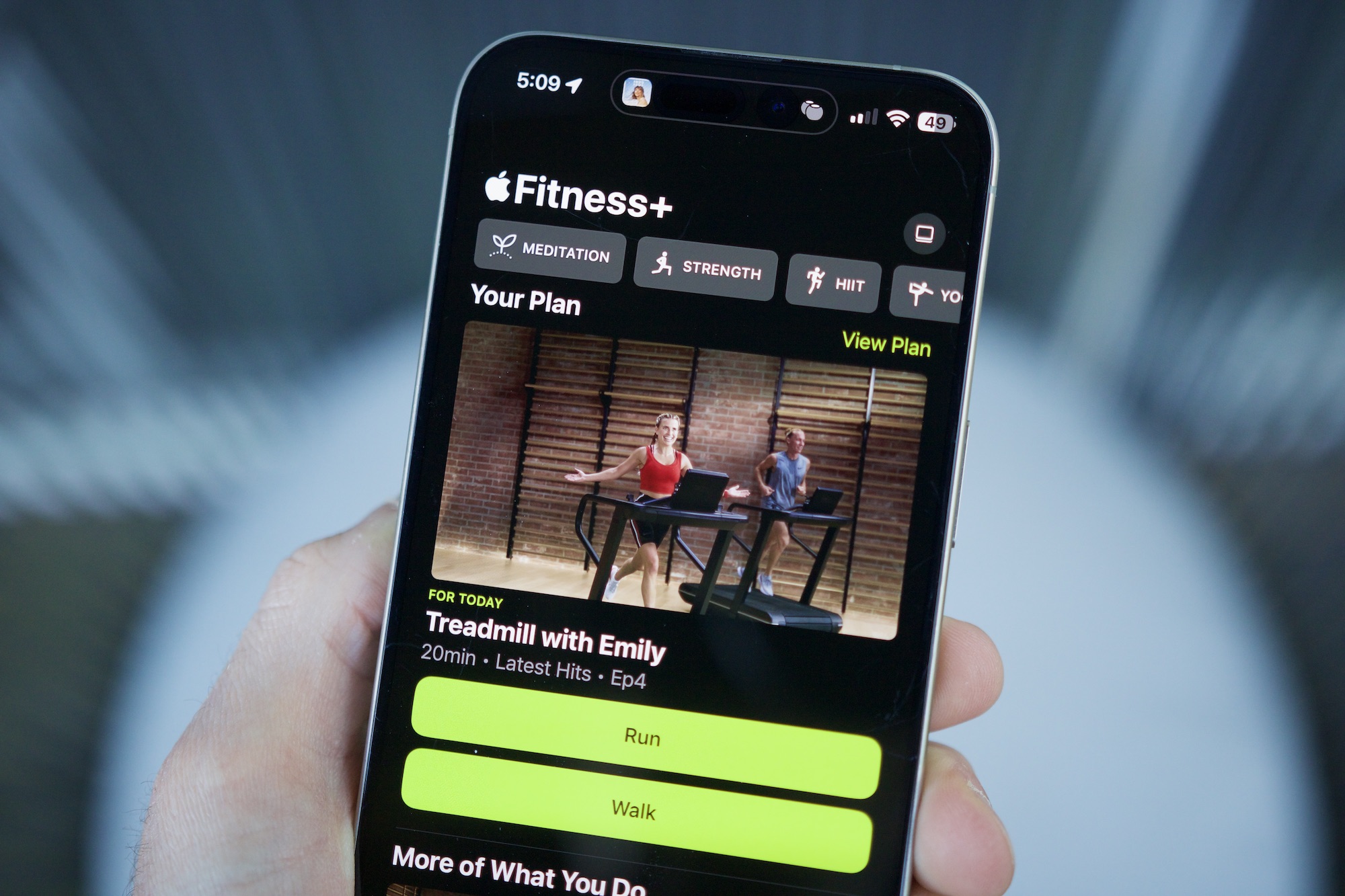 شخص يحمل جهاز iPhone مع فتح تطبيق Apple Litness ، مما يوضح ميزة الخطط المخصصة.