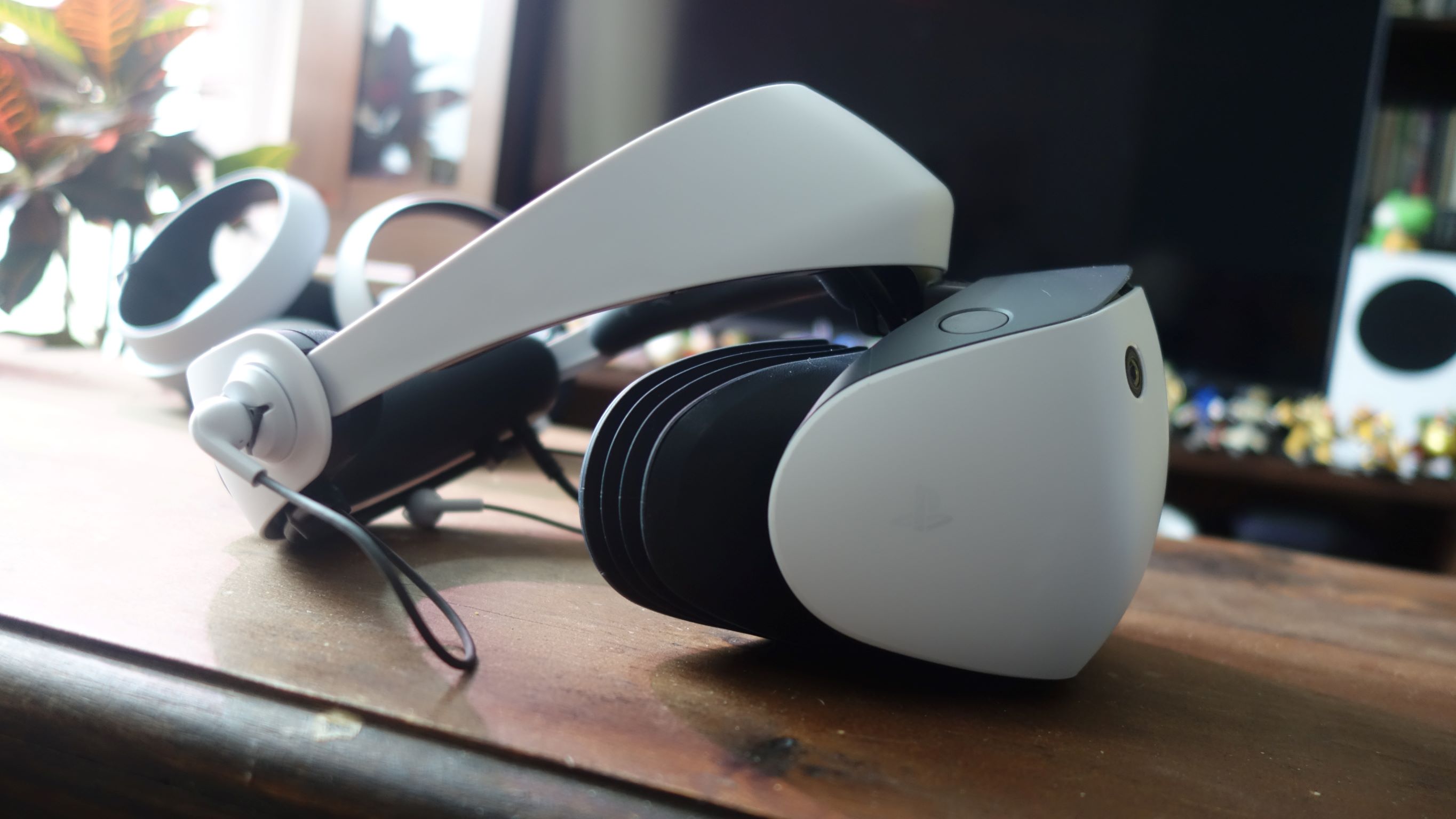 منظر جانبي لـ PlayStation VR2 ، الذي يجلس على طاولة خشبية.