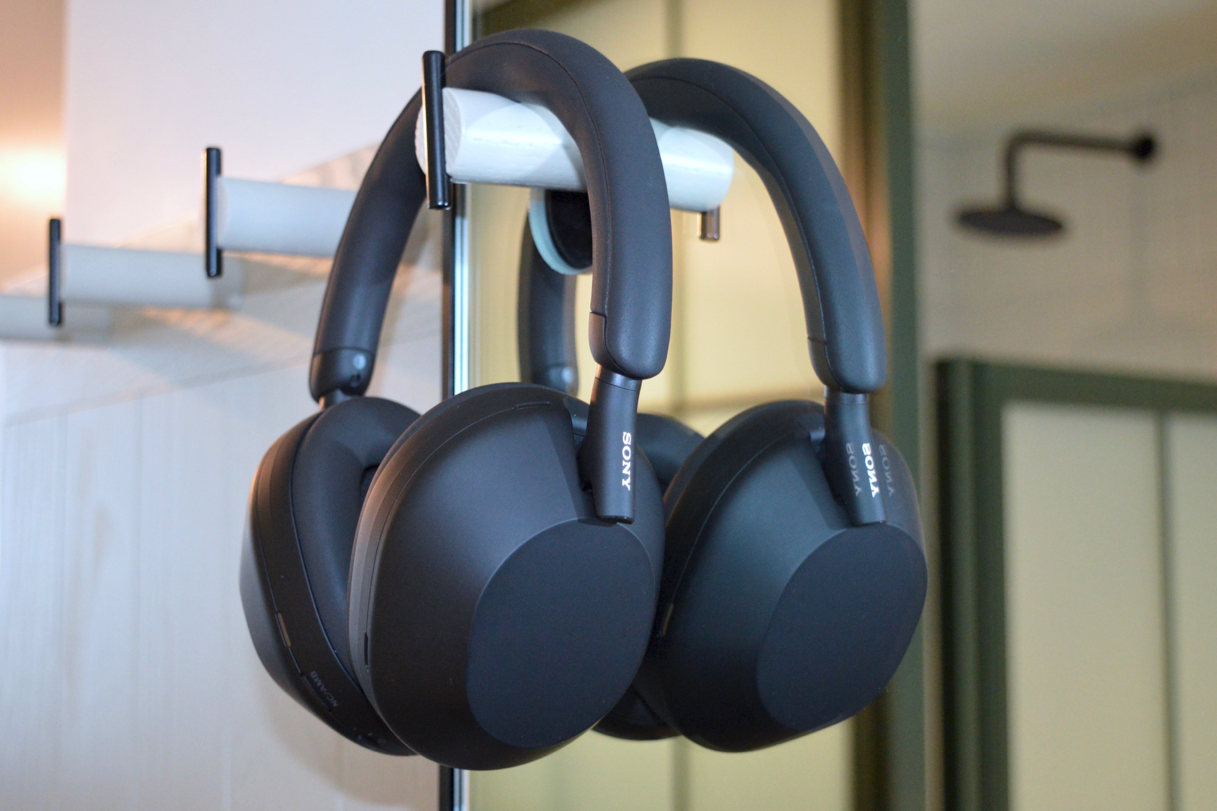 سماعات الرأس اللاسلكية Sony WH-1000XM5 معلقة على خطاف الجدار أمام المرآة.